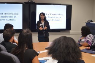 Vencore employee and recent George Mason graduate Gloria Rodriguez leads a biometrics presentation for students from the Thomas A. Edison AVID program at the Space Group STEM event on May 6, 2016.